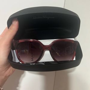 Salvatore Ferragamo burgundy sunglasses with gancini logos on the side.